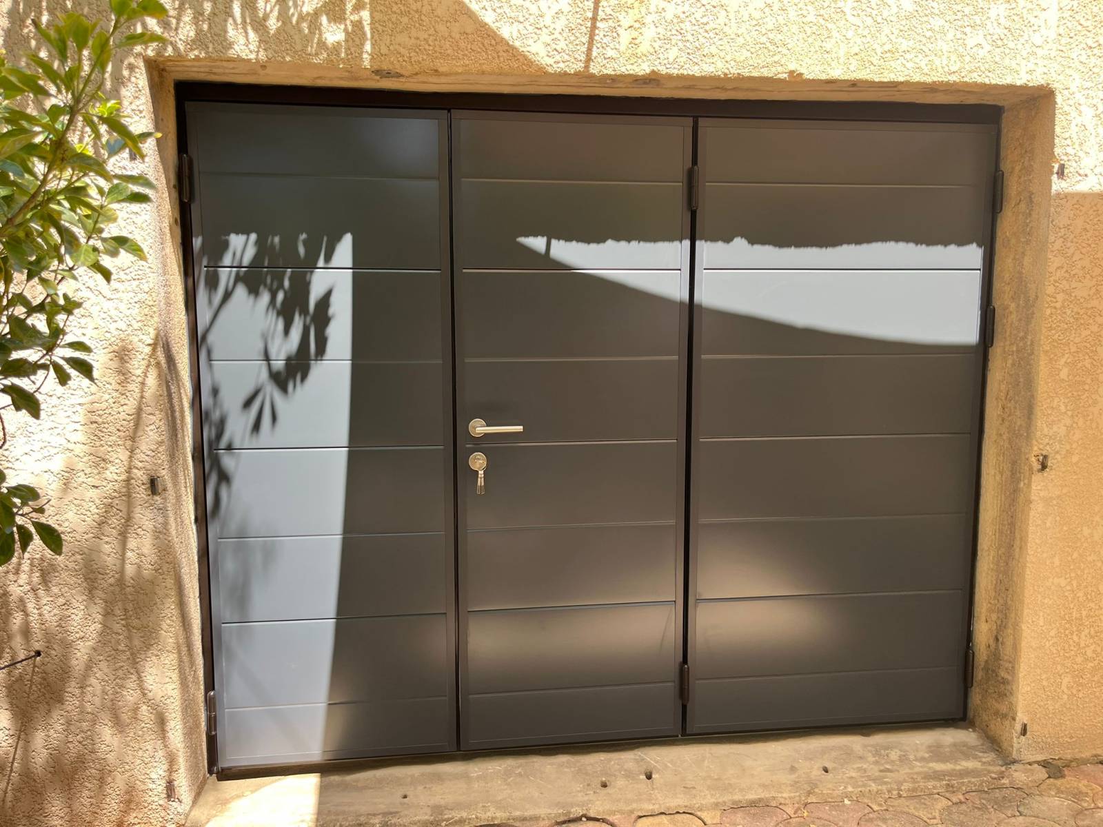 Mise en place d’une porte de garage battante manuelle à 3 battants sur Aramon, avec portillon centré et ouverture extérieure